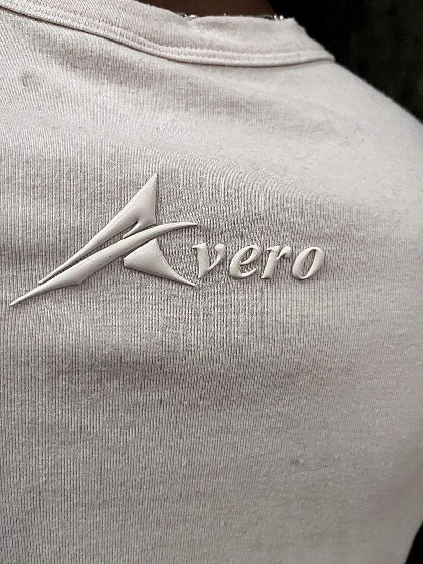 Close-up of the raised, tone-on-tone Avero logo on the back of the Sand tee